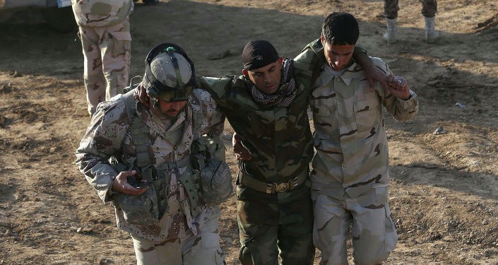 Iraqi soldiers help a wounded comrade in the area of Sayed Ghareeb, near Dujail, some 70 kilometres north of Baghdad