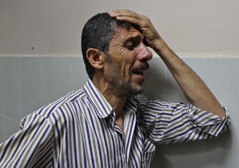 Mahmoud Obeid carries mourns his 7-year-old daughter Butheina, who was killed during an Israeli airstrike last night, at the morgue of the Indonesian hospital in Beit Lahia, in the northern Gaza Strip, on 16 May, 2021 (AFP)